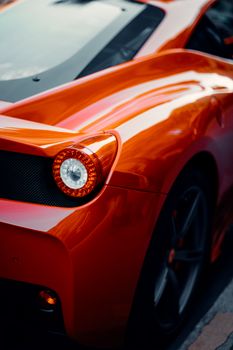 Detailed view of a sleek orange sports car highlighting its tail light and aerodynamic shape.