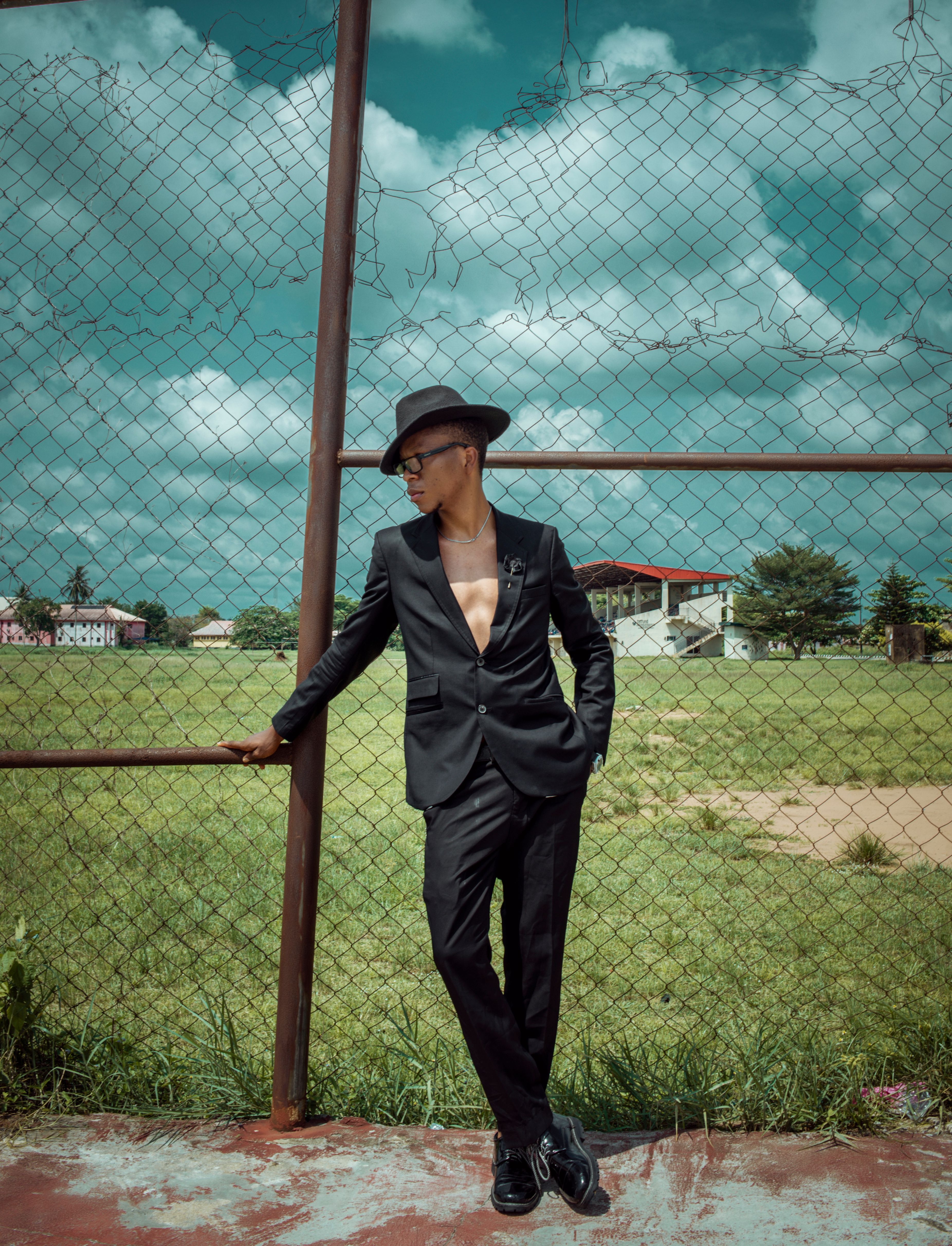 Stylish Man in Black Suit Leaning on Fence · Free Stock Photo