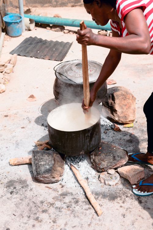Free Woman stirring large pot outdoors in Jos, Nigeria. Traditional cooking with firewood. Stock Photo