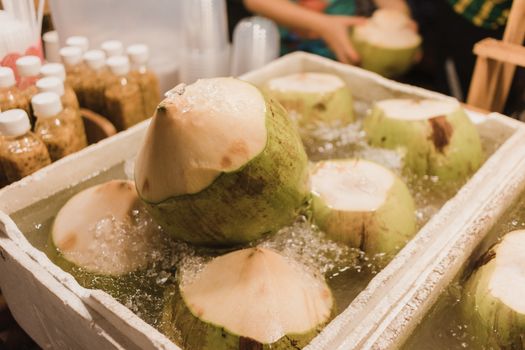 Chilled green coconuts submerged in ice, perfect for a refreshing tropical drink.