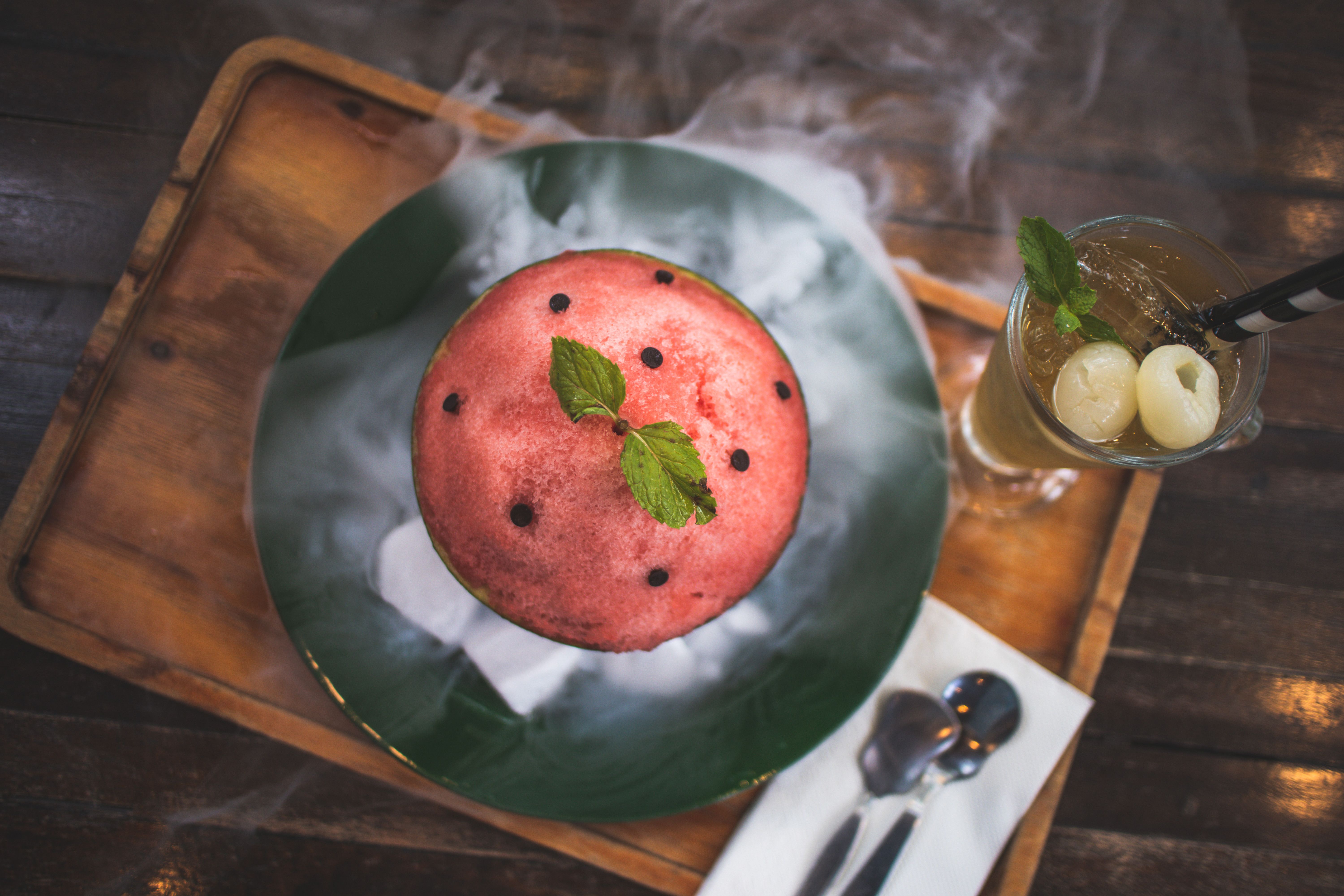 Top view of a watermelon-themed dessert and iced drink on a wooden tray, perfect for summer refreshment.