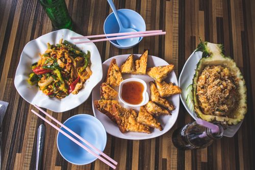 Free Delicious Asian dishes including stir fry, crispy wontons, and pineapple fried rice presented elegantly. Stock Photo