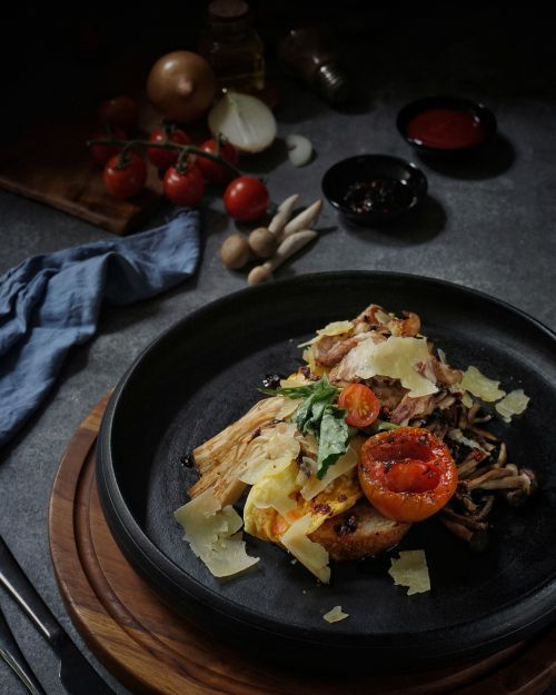 Free A close-up of a gourmet pasta dish with fresh tomatoes, mushrooms, and herbs, set in a rustic kitchen. Stock Photo