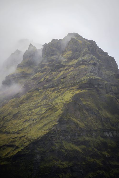 Free Dramatic mist-covered mountain peak with green slopes on a foggy island. Stock Photo