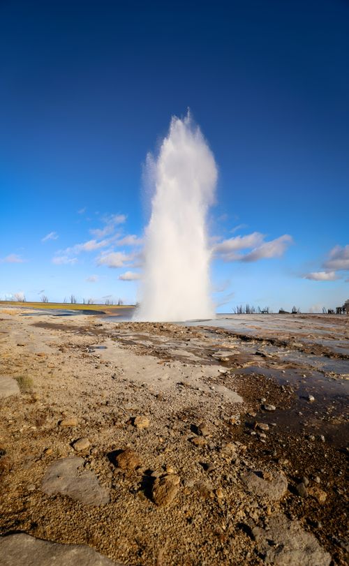 Free A spectacular geyser eruption captured in a natural island setting under a bright blue sky. Stock Photo