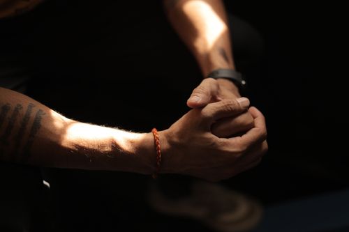 Free A contemplative pose with clasped tattooed hands, highlighting light and shadow play. Stock Photo