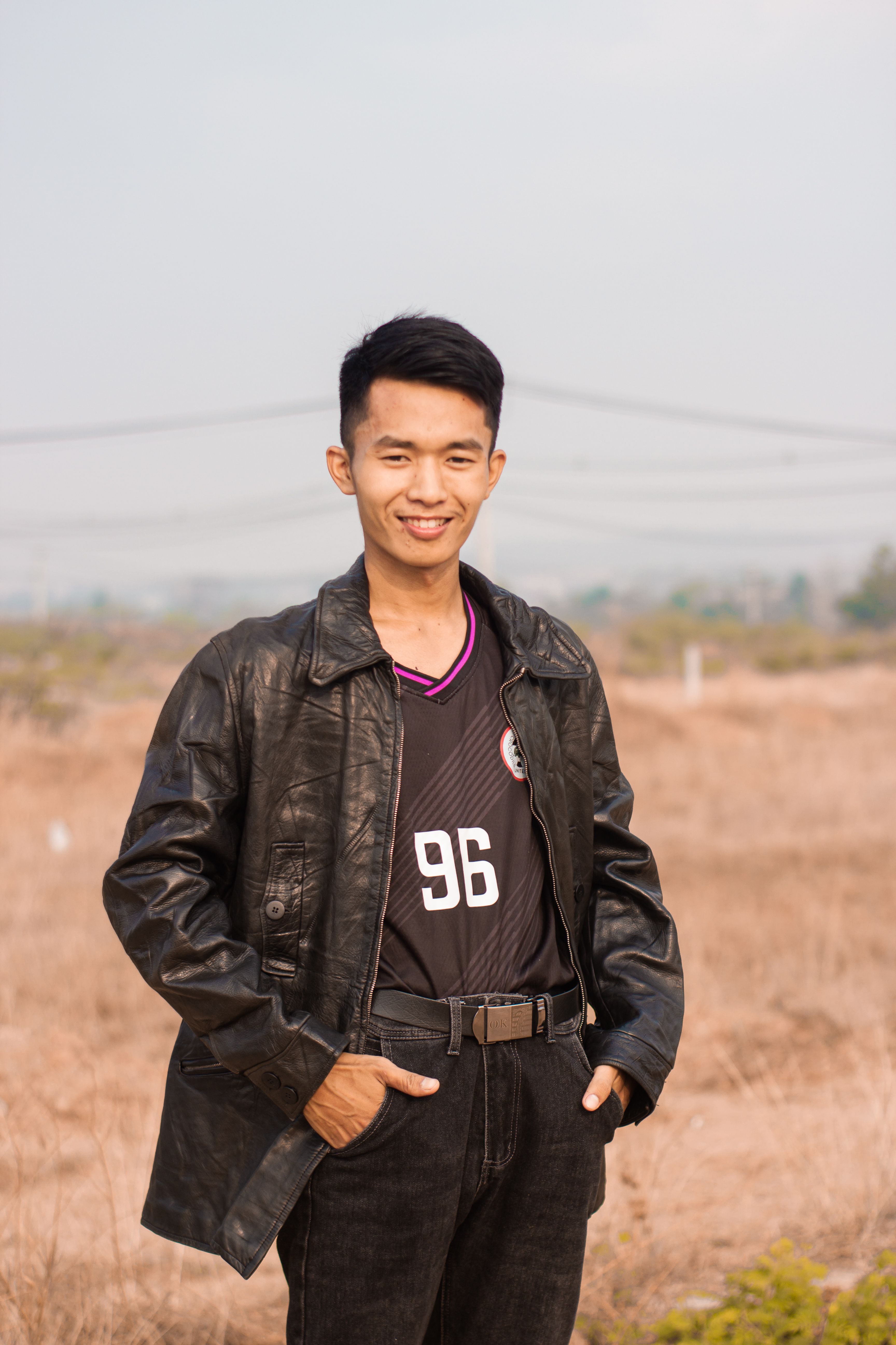 Portrait of a smiling man wearing a leather jacket standing outdoors in Myawaddy, Myanmar.
