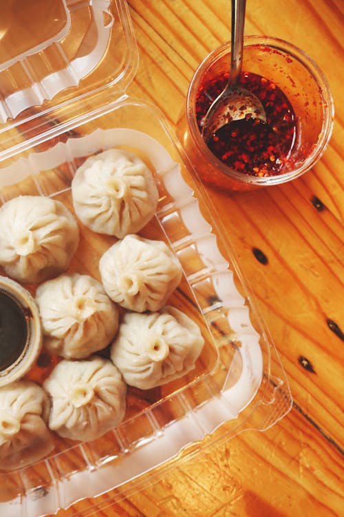 Dumplings in Plastic Container next to Sauce