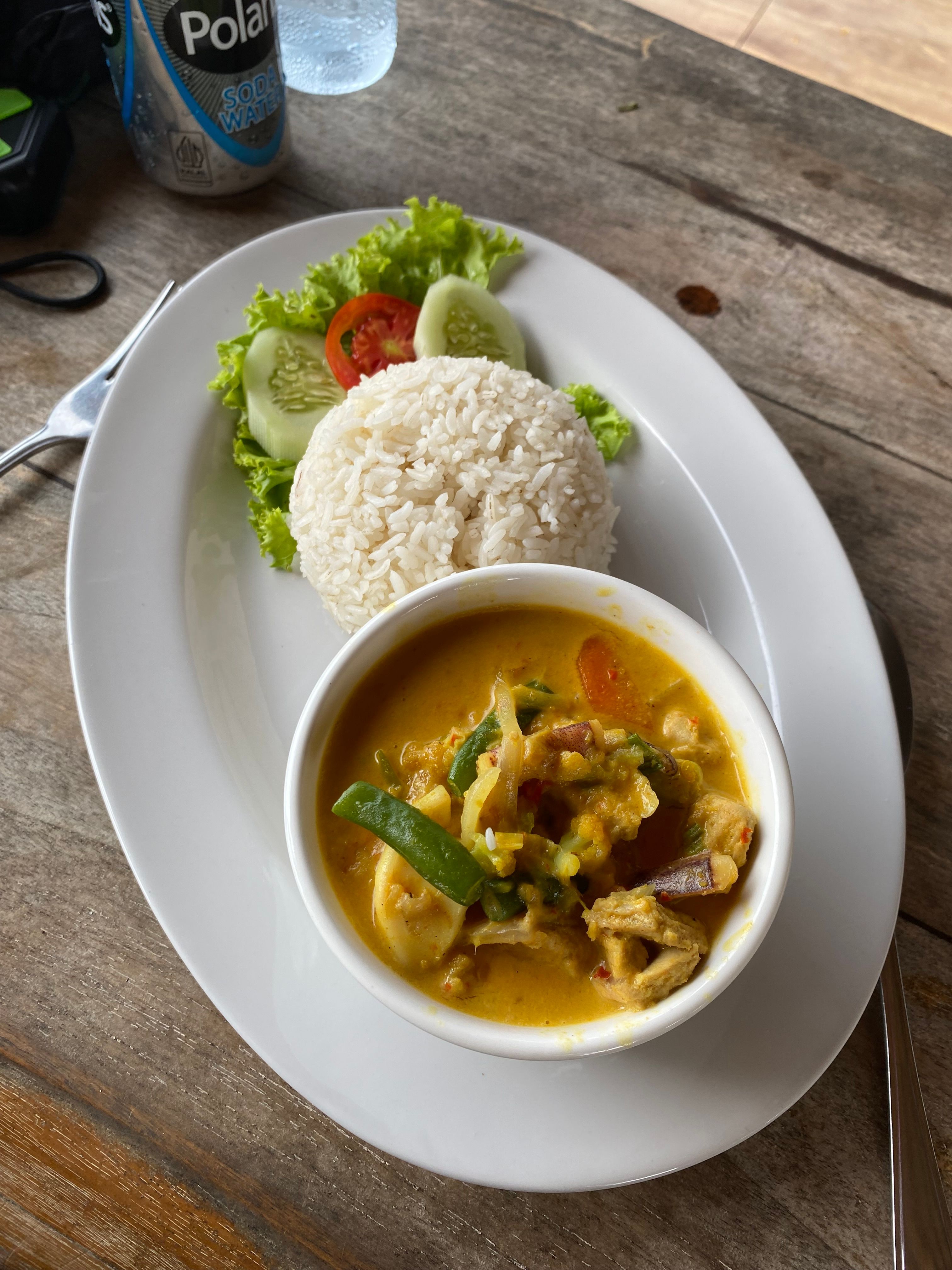 Tasty Thai curry and rice served with fresh salad on a wooden table.