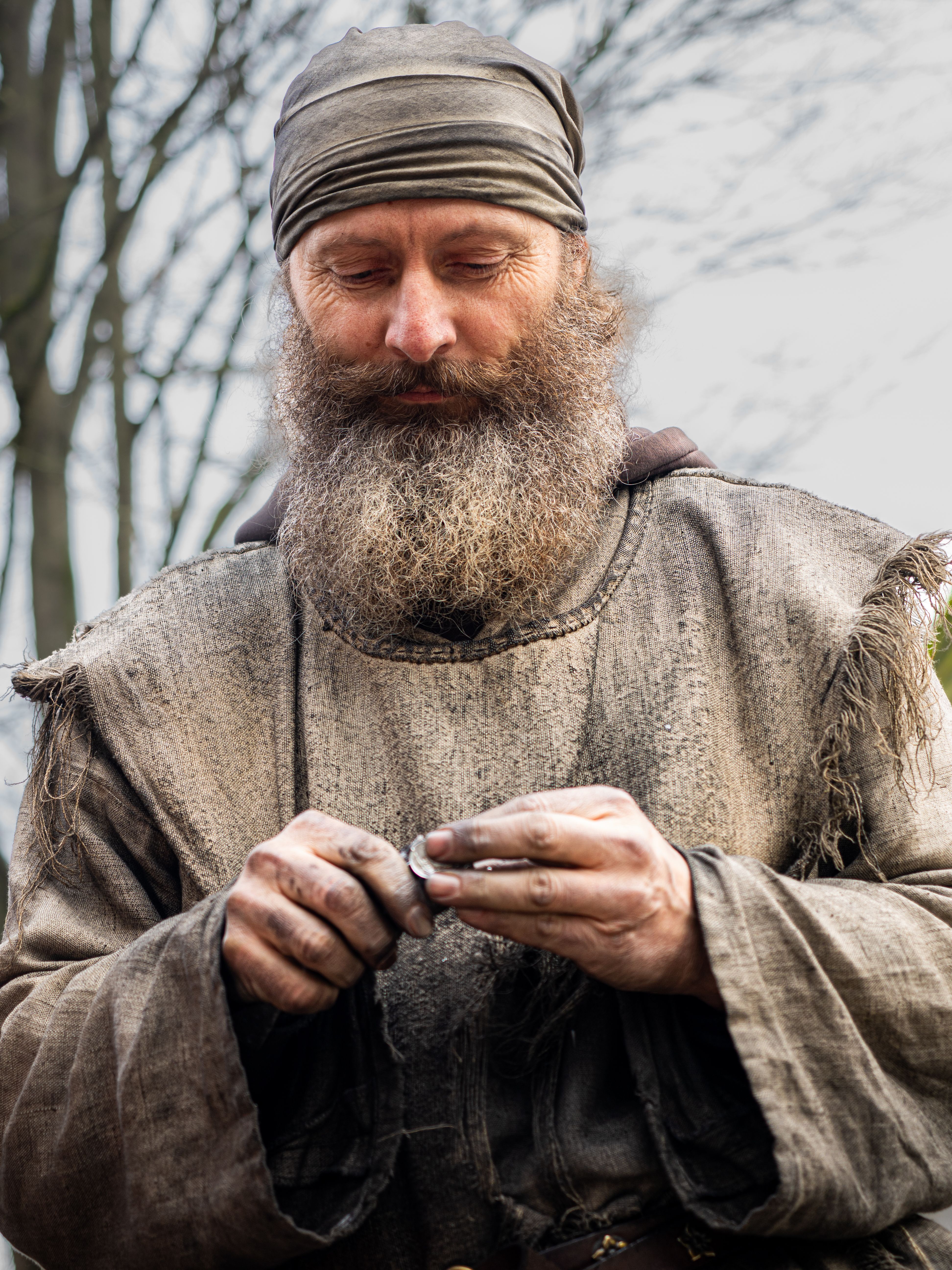 Portrait of a medieval craftsman working outdoors in rustic attire, surrounded by nature.
