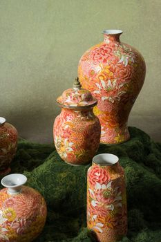 Ornate Asian porcelain vases with floral patterns displayed artistically on textured fabric.