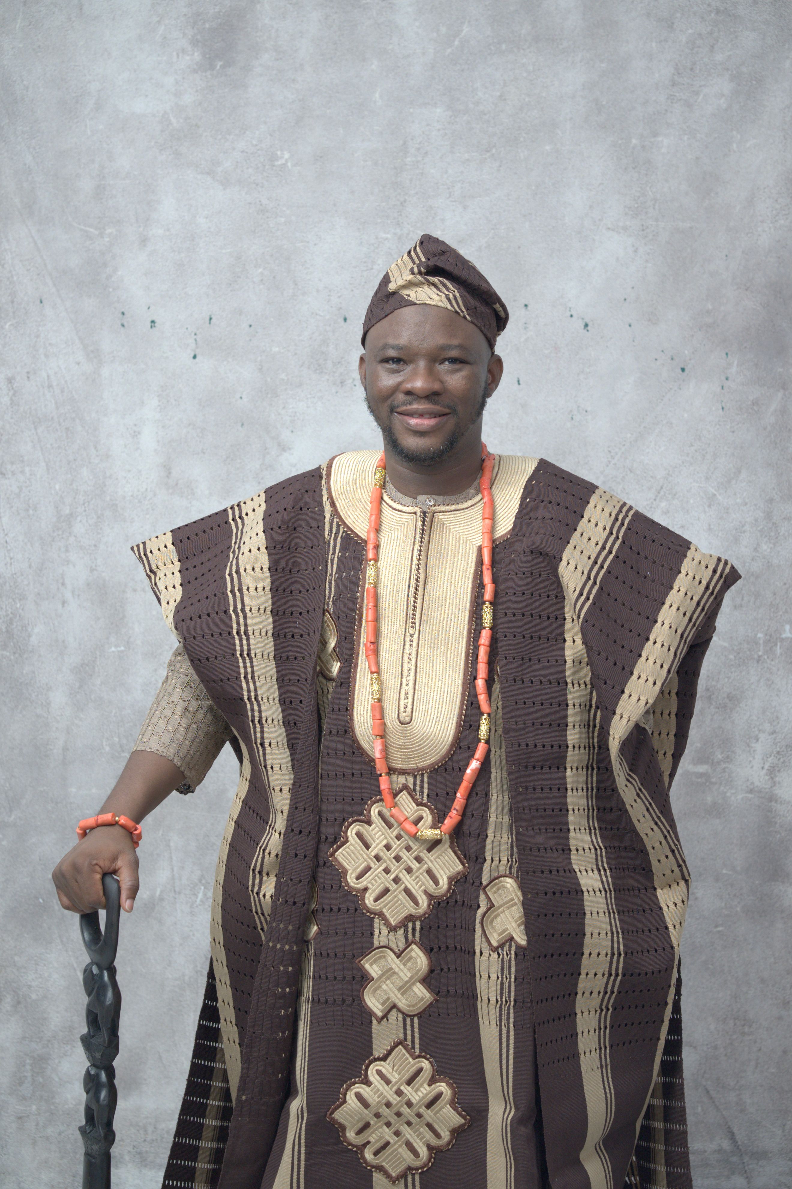 Smiling man in traditional Nigerian agbada outfit with ornaments.