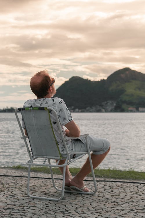 Man resting on chair near lake