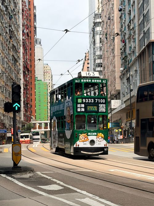 Free A classic double-decker tram navigating the busy streets of Hong Kong, surrounded by tall buildings and vibrant city life. Stock Photo