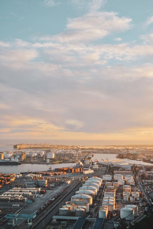 Free Aerial photo capturing Barcelona's industrial port during a stunning sunset, highlighting the city's industrial landscape. Stock Photo