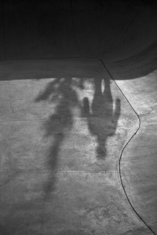 Free Black and white image of a shadow of a skateboarder on a concrete surface. Stock Photo