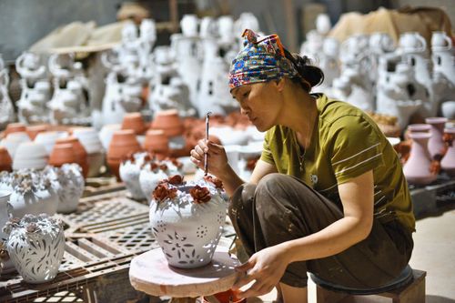 Free Focused artisan hand-painting intricate designs on ceramic vases in a pottery workshop. Stock Photo