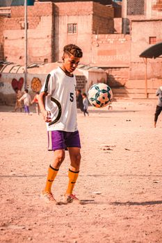 Young player practicing soccer skills in a rustic urban environment.