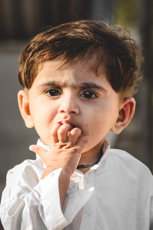 Free Close-up portrait of a cute baby in a white shirt outdoors during the day. Stock Photo