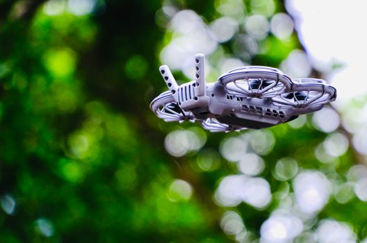 A close-up of a drone flying outdoors with a blurred green background, showcasing modern technology in Hong Kong.