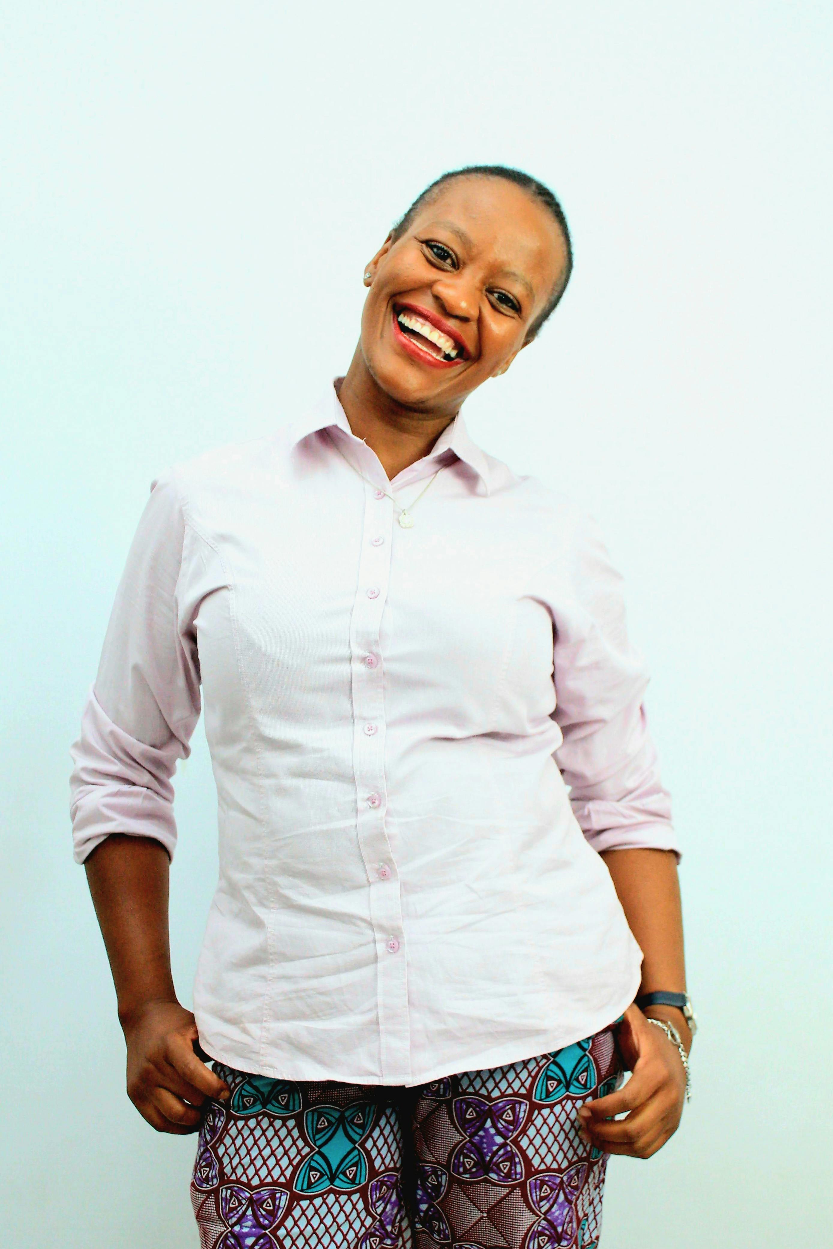 Cheerful woman posing in a light shirt and patterned pants. Captured in South Africa.