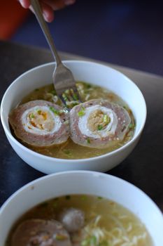 A delectable Asian noodle soup topped with sliced meat rolls, garnished with green onions.