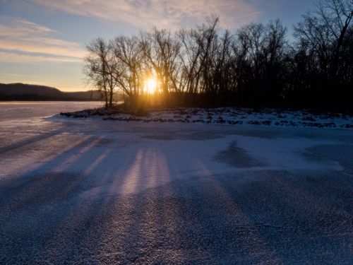 Free Beautiful winter sunset over a frozen lake with silhouetted trees in West Newton, Minnesota. Stock Photo