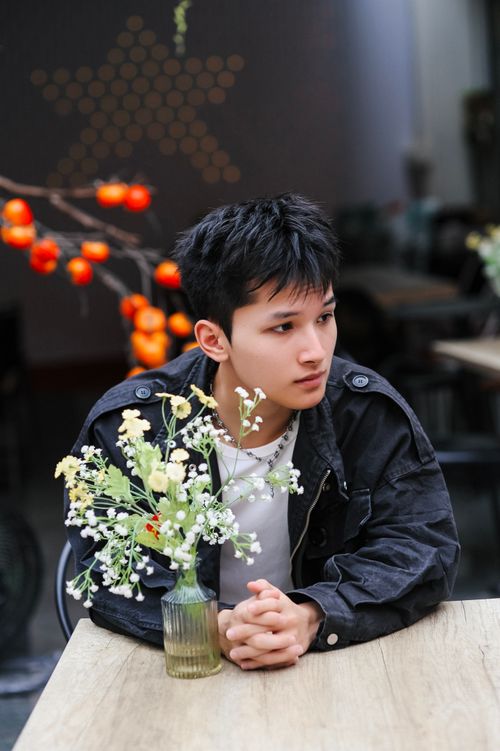 Free Young man in a café with flowers, lost in thought. Warm, cozy ambiance. Stock Photo