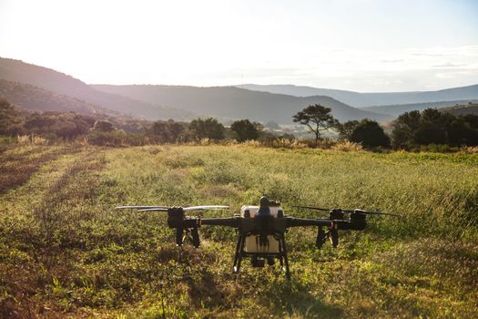 A drone ready for takeoff on a scenic agricultural field, capturing a beautiful sunrise.