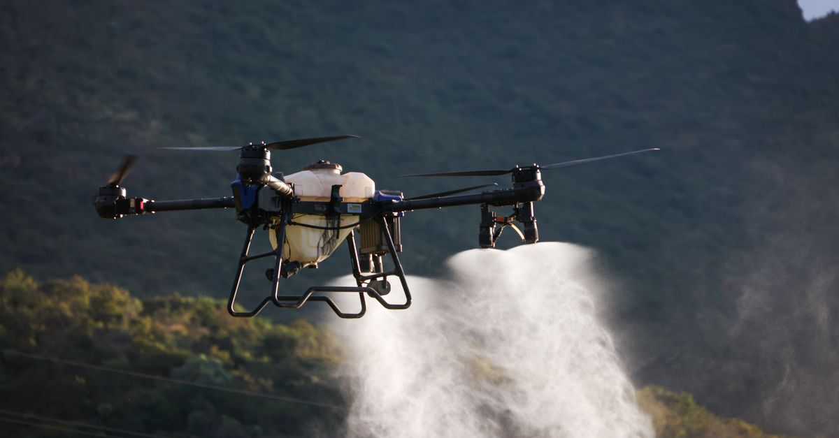 Drone dispersing spray over farmland, showcasing modern agriculture techniques.