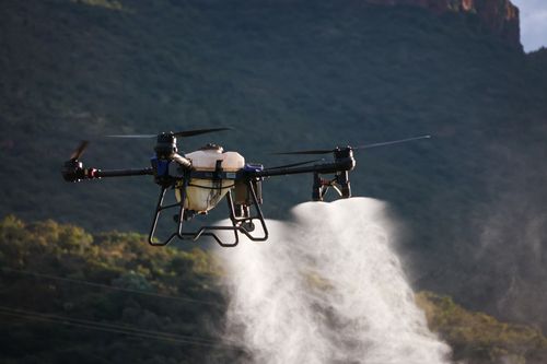 Free Drone dispersing spray over farmland, showcasing modern agriculture techniques. Stock Photo