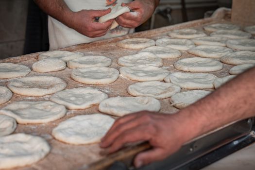 Artisan bakers shaping fresh pita bread dough by hand in a traditional bakery setting.
