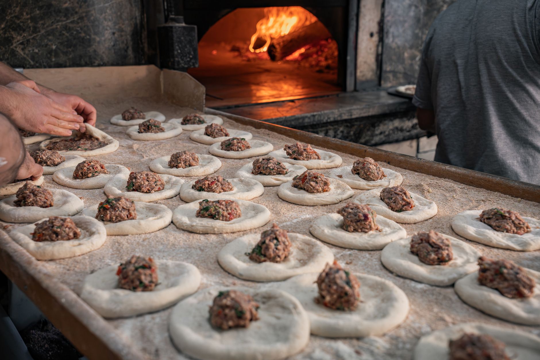 Handmade Middle Eastern meat pies being prepared for baking in a traditional oven. Fresh and authentic.