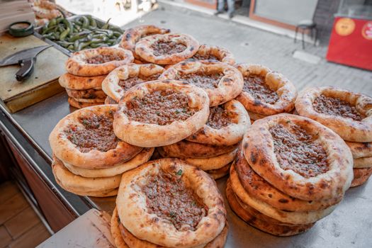 Delicious stacks of freshly baked Turkish pide with savory toppings, ready to be served in a street market setting.