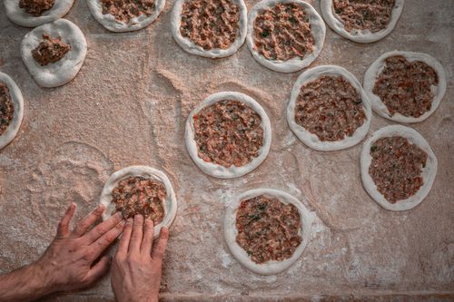 Free Hands shaping lahmacun with meat and dough, showcasing a traditional Turkish dish. Stock Photo