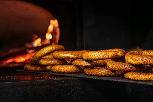 Free Golden bread rings baked in a traditional oven with visible flames creating a rustic ambiance. Stock Photo