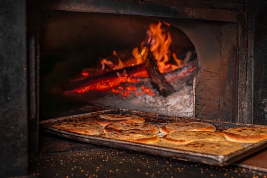 Rustic bread baking in a traditional wood-fired oven, showcasing the rich texture and flame-cooked method.