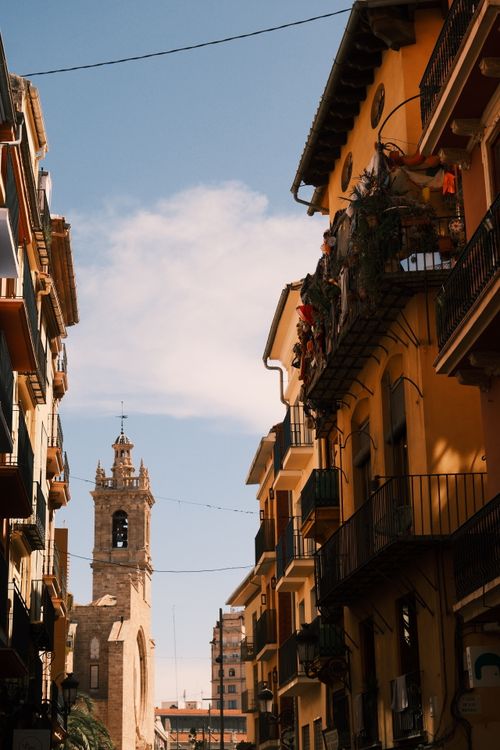 Free Charming European street view with historic architecture and church tower under a clear blue sky. Stock Photo