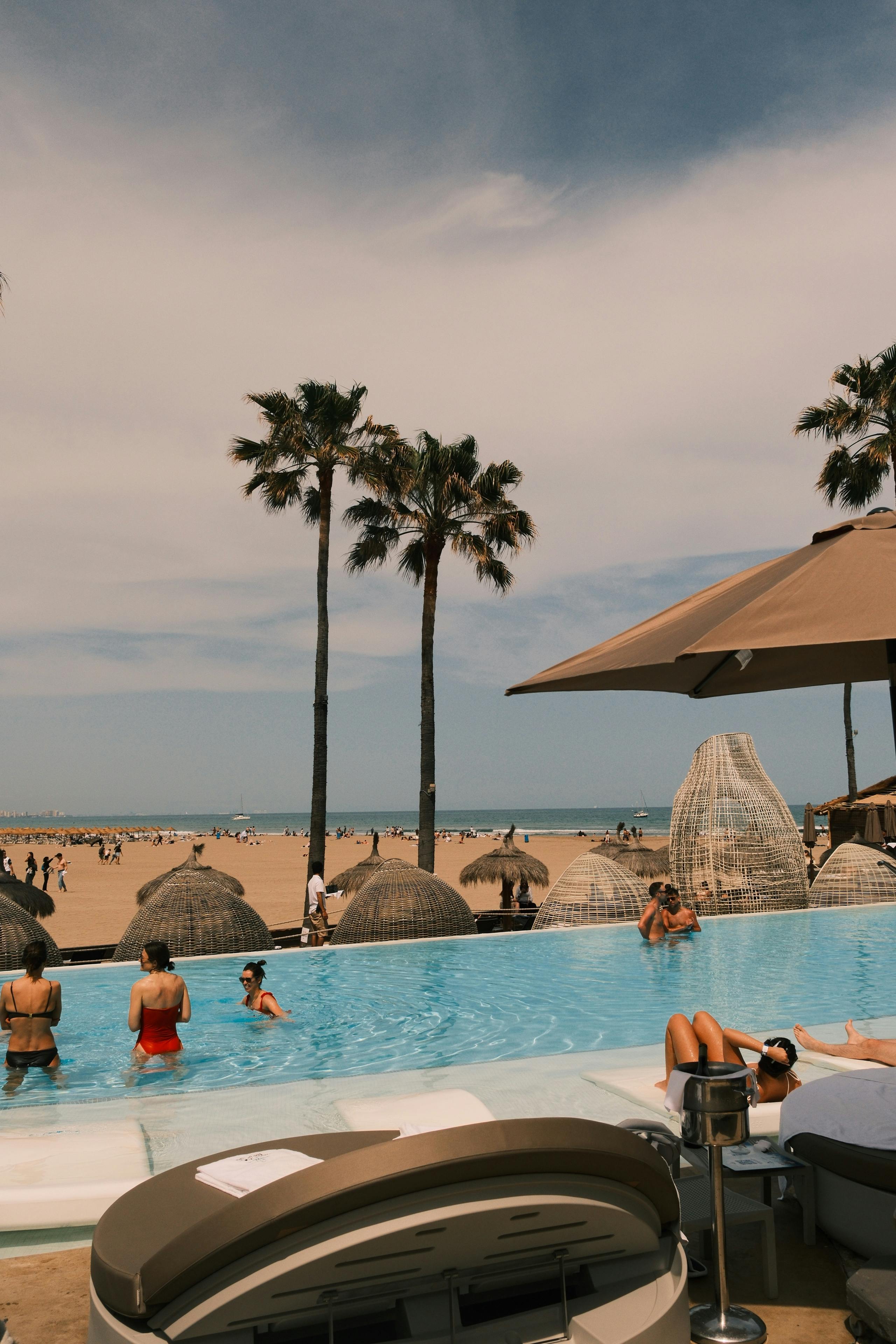 Rows of daybeds with white umbrellas at one of the best beach clubs in Bali on Canggu's Berawa Beach in the afternoon