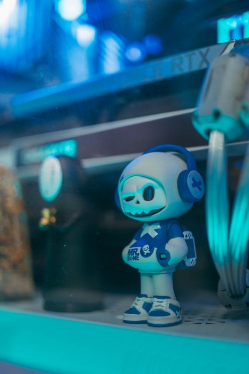 Free A vibrant skull-themed toy figurine under neon blue lighting in a futuristic setting. Stock Photo