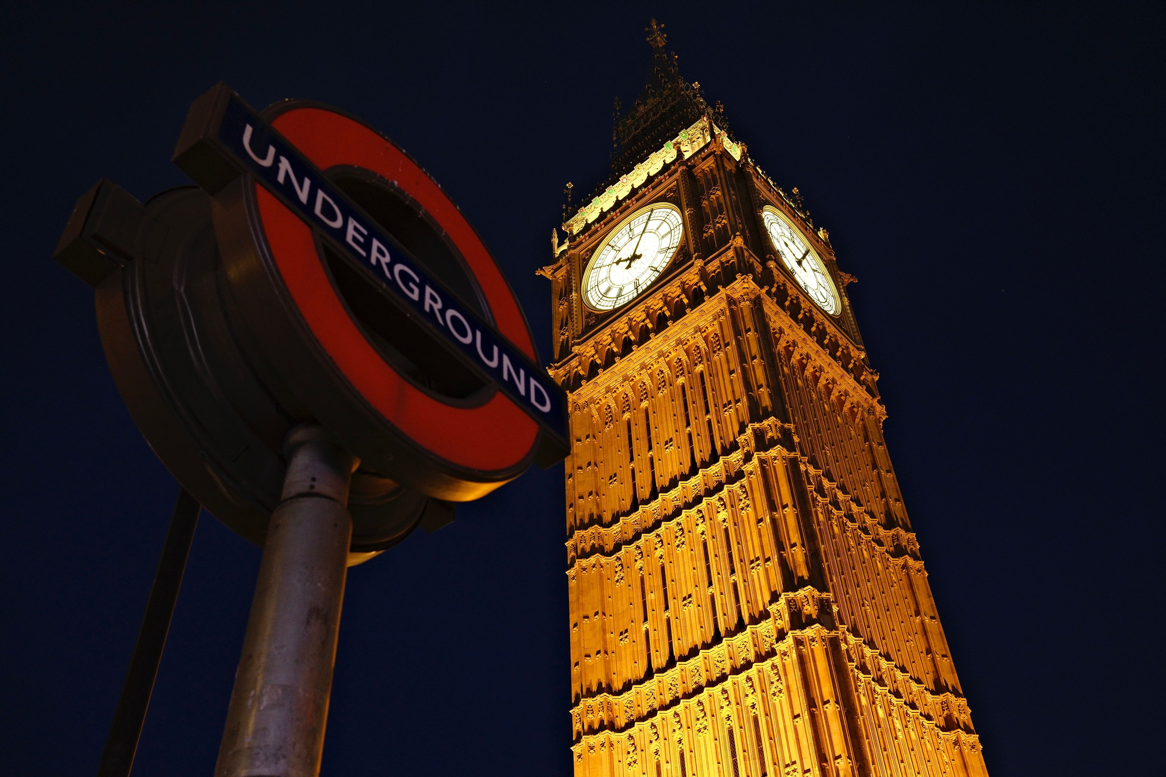 Stunning night view of Big Ben in London with an Underground sign in the foreground.