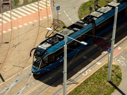 Free Aerial view of a modern tram in Wrocław, Poland, navigating city streets with visible bike lane. Stock Photo