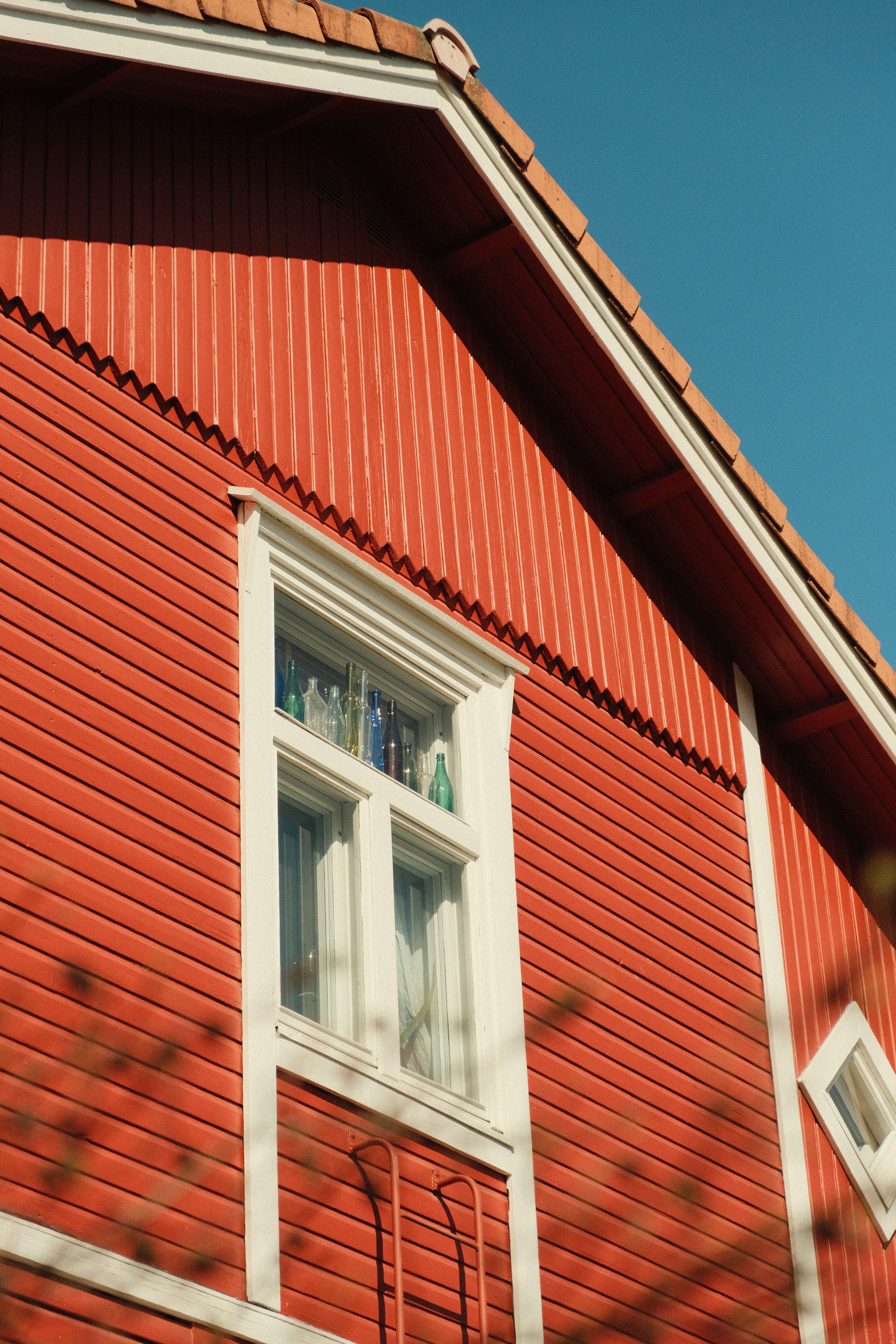 Close-up of a vibrant red wooden house facade under clear blue skies in Lahti, Finland.