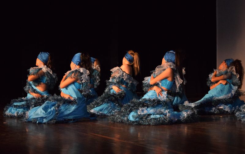 Dancers in blue costumes performing on a darkened stage — photo by Camilo Muñoz on Pexels