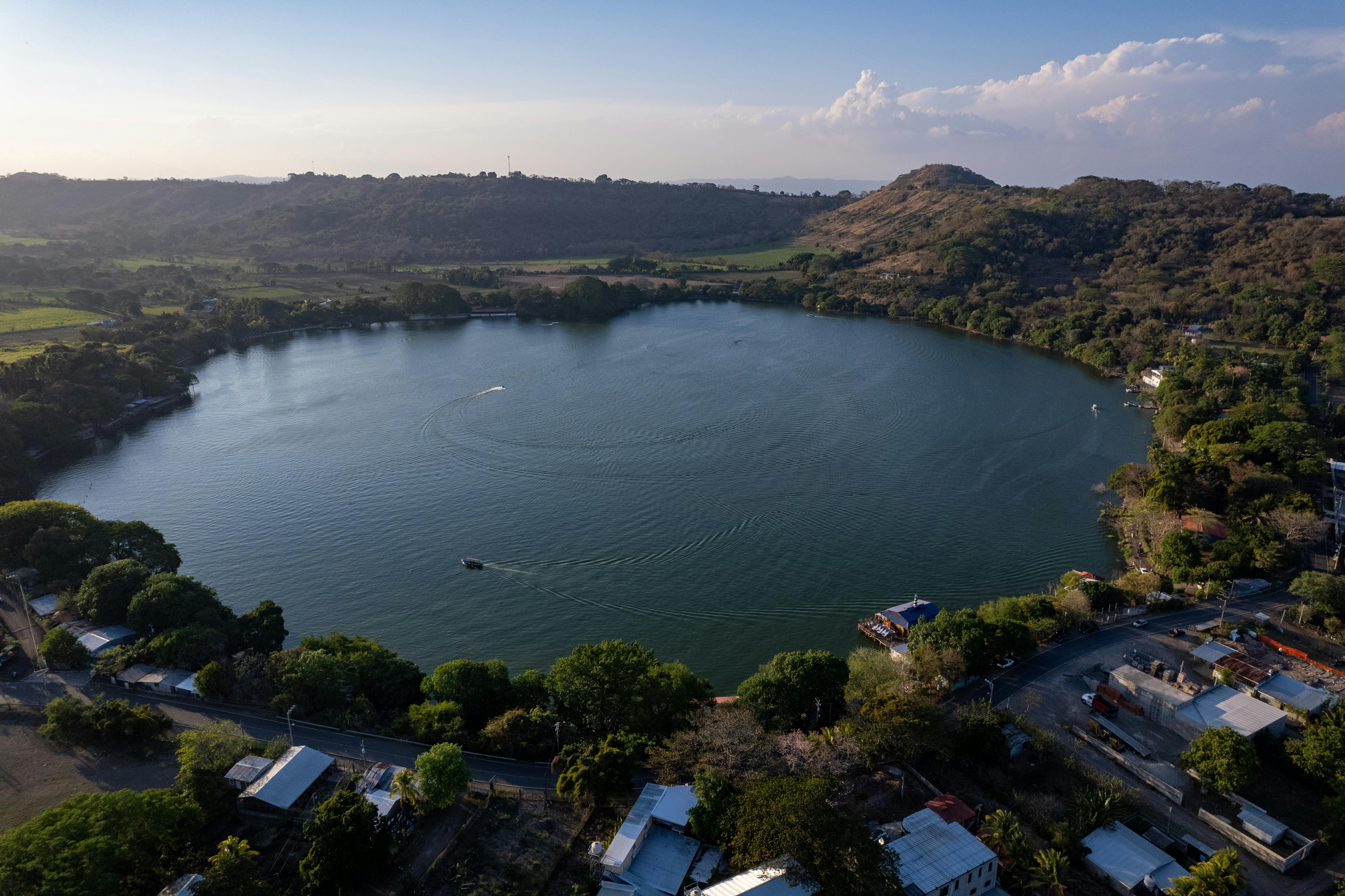 Stunning aerial view of Lake Apastepeque surrounded by lush hills and buildings at daytime.