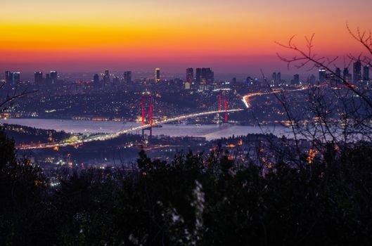 A stunning sunset view over İstanbul featuring the illuminated Bosphorus Bridge and city skyline.