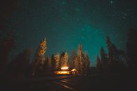 宁静的夜色中，一间舒适的小屋坐落在绿树成荫的星空下