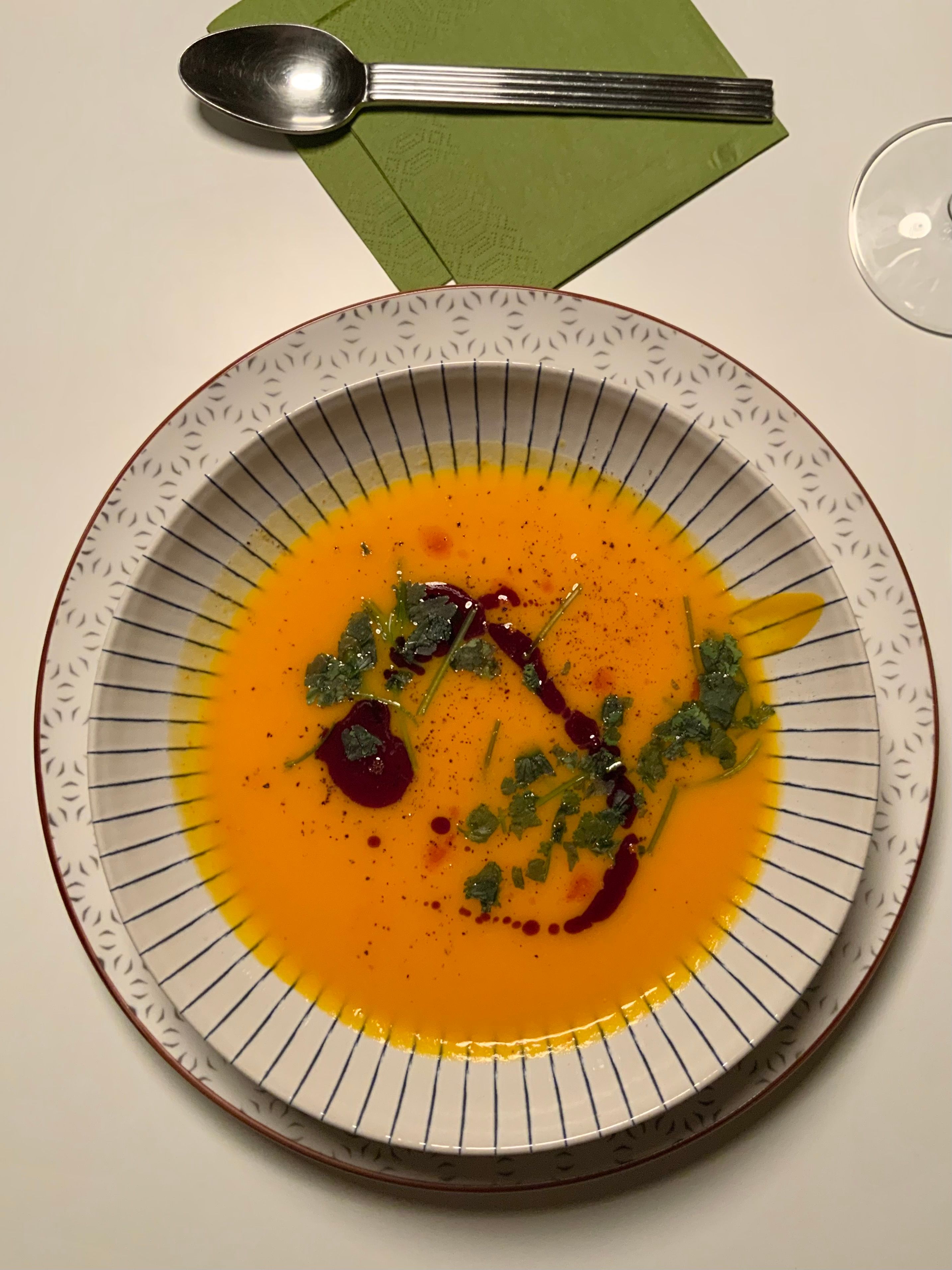 Aerial view of a gourmet pumpkin soup garnished with herbs, served elegantly.