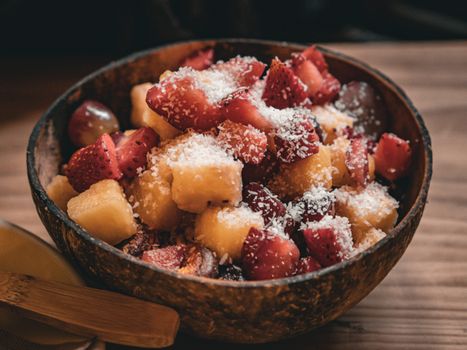 A vibrant fruit bowl filled with fresh tropical fruits and sprinkled with coconut flakes.
