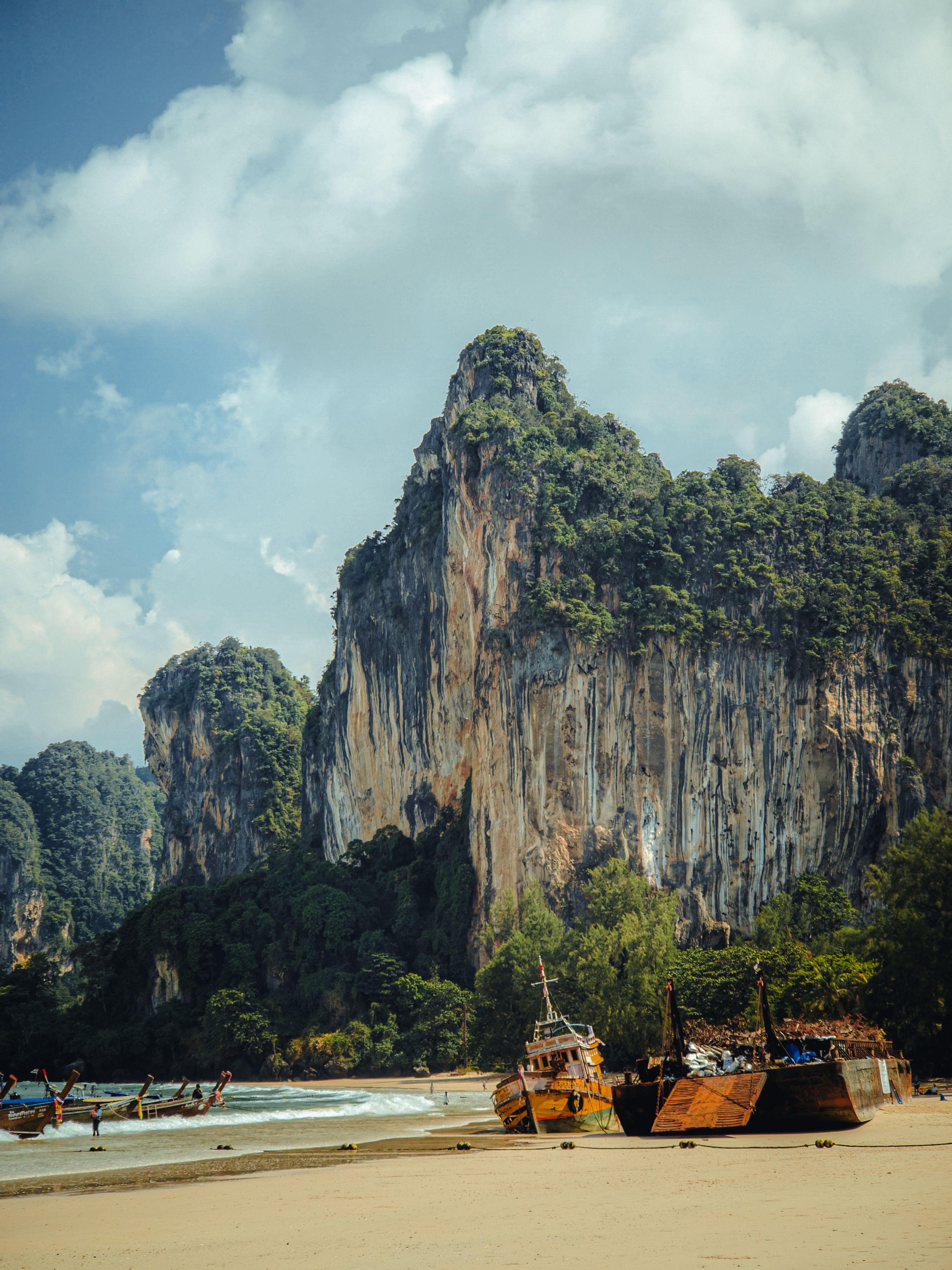 Majestic limestone cliffs by the beach with boats in Krabi, Thailand.